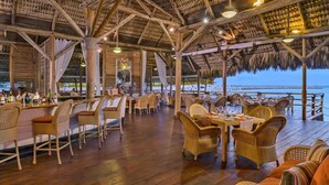 An outdoor restaurant with wooden furniture and a thatched roof. - One-of-a-kind Villa With Open Spaces and Amazing Views in Luxury Beach Resort (Punta Cana)