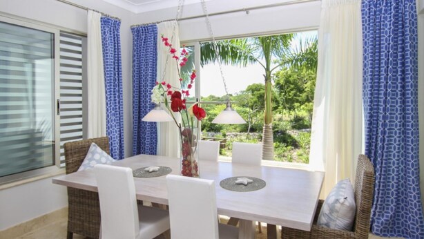 A dining area with a white table, white chairs, and a vase with flowers.