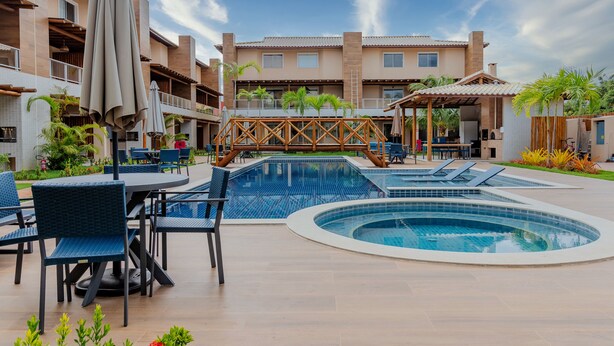 A pool area with multiple seating arrangements and a covered patio. - IT28 Triplex 4 Suítes 100m da Praia (Camaçari)