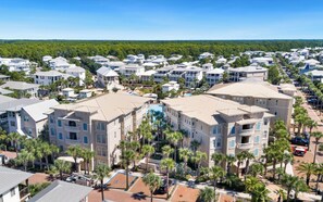 A residential area with multiple two-story buildings, a swimming pool, and palm trees. - New Rental in Seacrest Beach Resort, stunning views of Lagoon Pool, 3 bikes! (Panama City Beach)