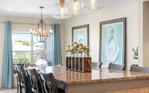 A modern kitchen with a granite countertop, bar stools, a hanging light fixture, and a vase with flowers. - New Rental in Seacrest Beach Resort, stunning views of Lagoon Pool, 3 bikes! (Panama City Beach)