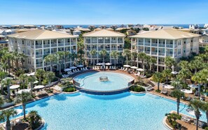 A resort with a large central pool, multiple balconies, and palm trees. - New Rental in Seacrest Beach Resort, stunning views of Lagoon Pool, 3 bikes! (Panama City Beach)