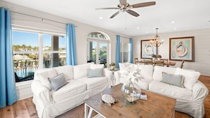 A spacious living room with a white sectional sofa, a wooden coffee table, and a ceiling fan. - New Rental in Seacrest Beach Resort, stunning views of Lagoon Pool, 3 bikes! (Panama City Beach)
