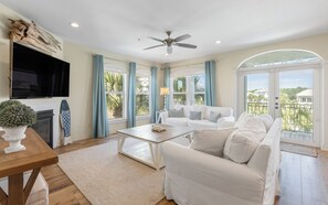A spacious living room with a white sofa, a coffee table, and a TV mounted on the wall. - New Rental in Seacrest Beach Resort, stunning views of Lagoon Pool, 3 bikes! (Panama City Beach)