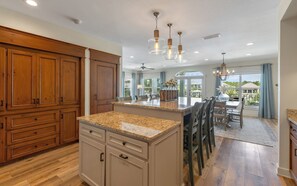 A spacious kitchen with wooden cabinets, granite countertops, and pendant lighting. - New Rental in Seacrest Beach Resort, stunning views of Lagoon Pool, 3 bikes! (Panama City Beach)