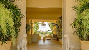 A corridor with a view of a garden, two white animal statues, and potted plants. - Luxurious Fully-staffed Villa With Amazing View in Exclusive Golf Beach Resort (Punta Cana)