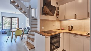 Une cuisine moderne dotée d’un four encastré, d’un plan de travail en bois et d’un coin repas avec une table et des chaises.