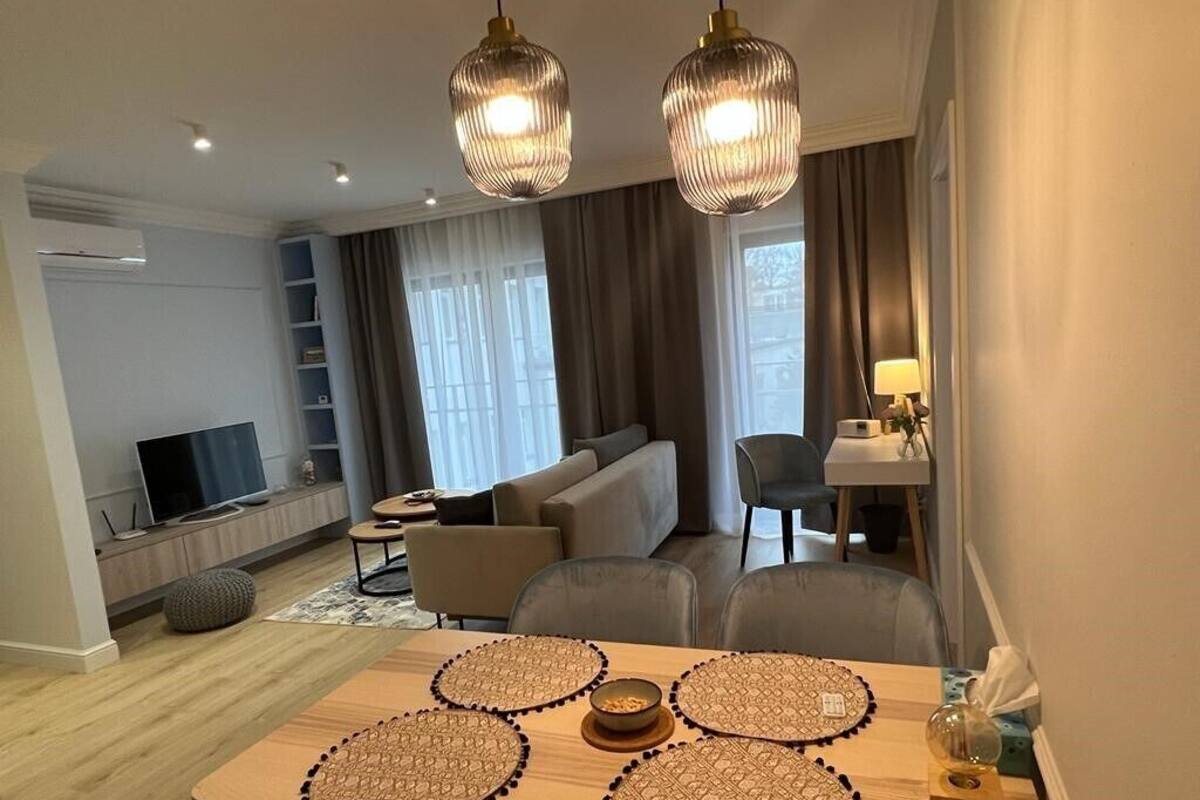 Una sala de estar moderna con sofá, mesa de comedor y televisor.