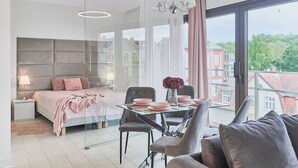 Un dormitorio moderno con cama, mesita de noche, lámpara y un área de comedor con sillas y mesa.