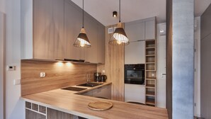 Une cuisine moderne avec des comptoirs en bois, un évier et une machine à café. Deux lampes suspendues sont fixées au-dessus du comptoir.