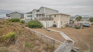 A multi-story residential building with a covered porch and a small staircase leading to the entrance. - The Captain's Quarters 2 Bedroom Home by RedAwning (Supply)