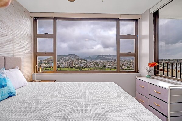 Quarto com uma janela grande, uma cama, um penteado e uma mesa de cabeceira.