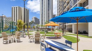 A courtyard with outdoor seating, a playground, and tall buildings in the background.