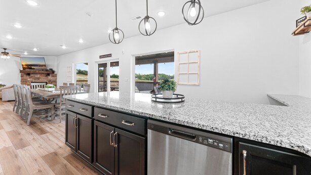 A modern kitchen with granite countertops, stainless steel appliances, and pendant lighting.