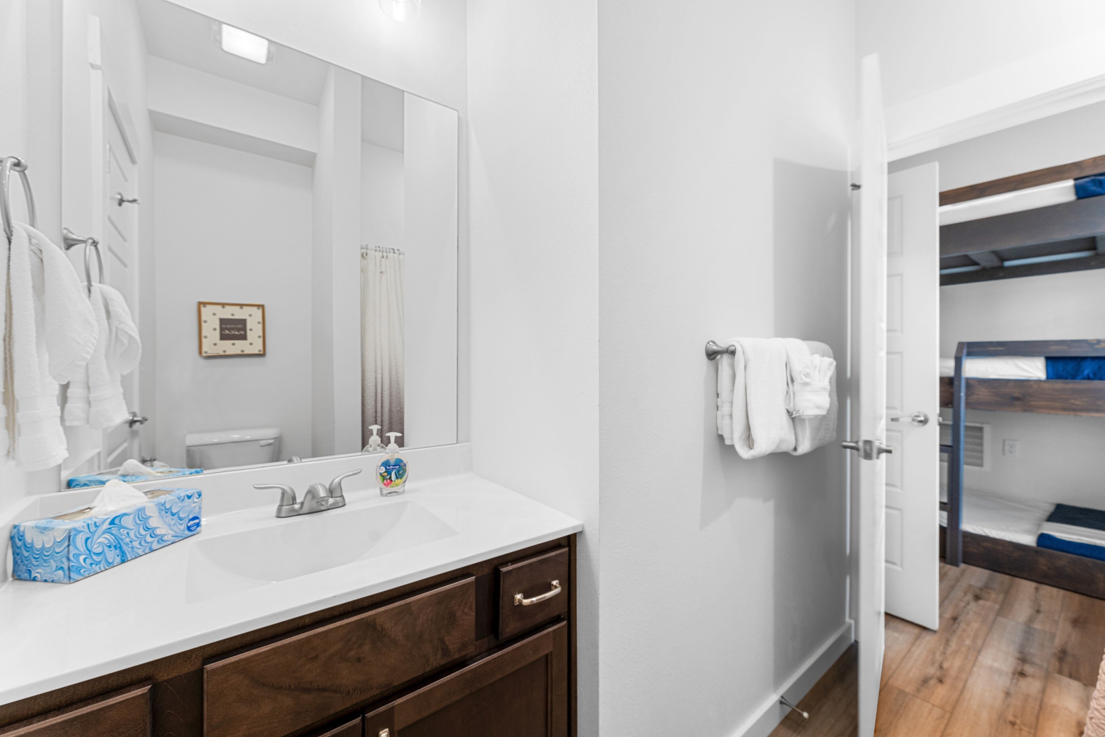A bathroom with a white sink, a large mirror, and a wooden vanity.