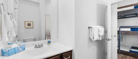 A bathroom with a white sink, a large mirror, and a wooden vanity.
