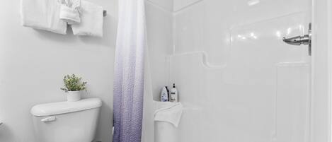 A bathroom with a toilet, a shower with a gradient curtain, and a towel rack with a towel.