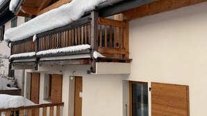 Um edifício de dois andares com varandas de madeira cobertas de neve, portas de madeira e uma pequena janela.
