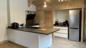 Uma cozinha moderna com ilha central, vigas de madeira no teto e eletrodomésticos embutidos.