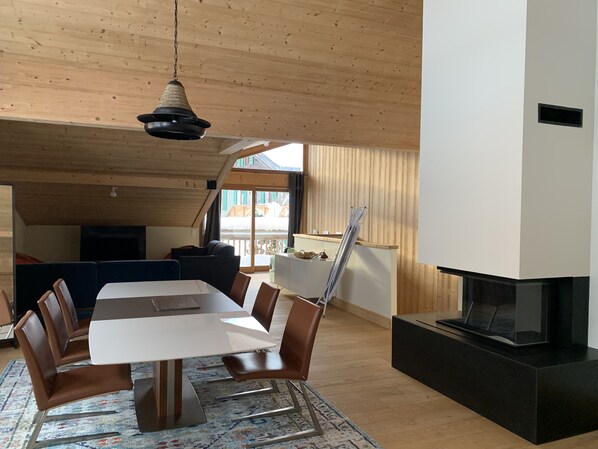 A modern dining area with a wooden ceiling, a large table, and brown chairs.