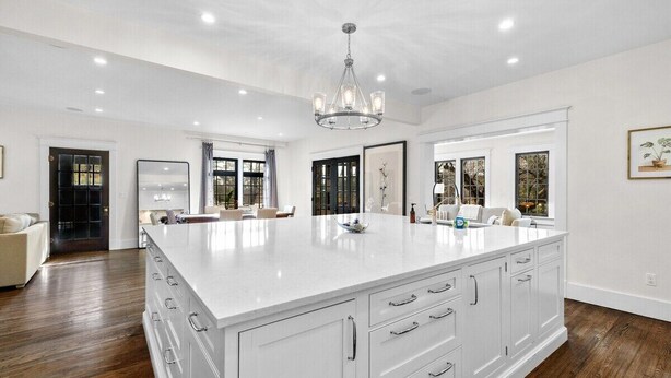 A spacious kitchen with a large island, white cabinetry, and a chandelier.