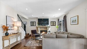 A living room with a fireplace, a sofa, a chair, and a console table with a lamp.