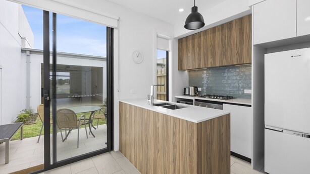 A modern kitchen with a wooden island, white cabinets, and a built-in stove.