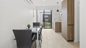 A modern kitchen with a dining area, featuring a glass door leading to a balcony.