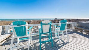 Um terraço com três cadeiras Adirondack turquesa voltado para a praia.