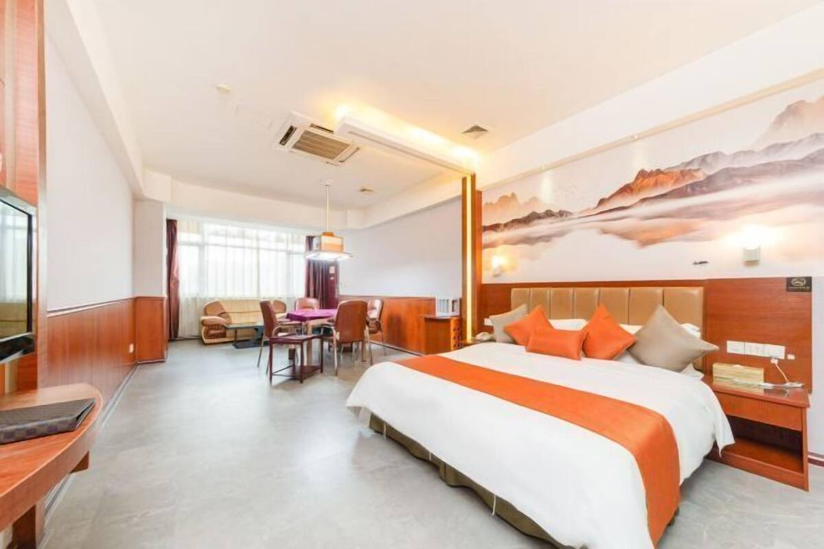 A hotel room with a large bed, a desk, and a chair.