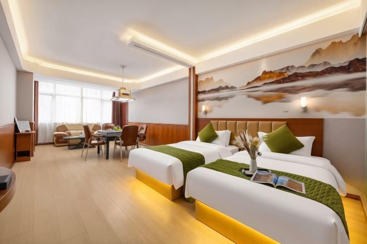 A hotel room with two beds, a dining area, and a large window.