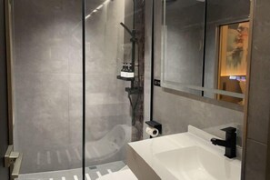 A modern bathroom with a glass shower enclosure, a white sink, and a black faucet. - Forbes Hotel (Shenzhen Longhua Dalang Commercial Center) (Shenzhen)