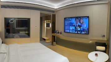 Habitación de hotel moderna con una cama grande, un televisor montado en la pared, una mesita y un rincón de descanso.