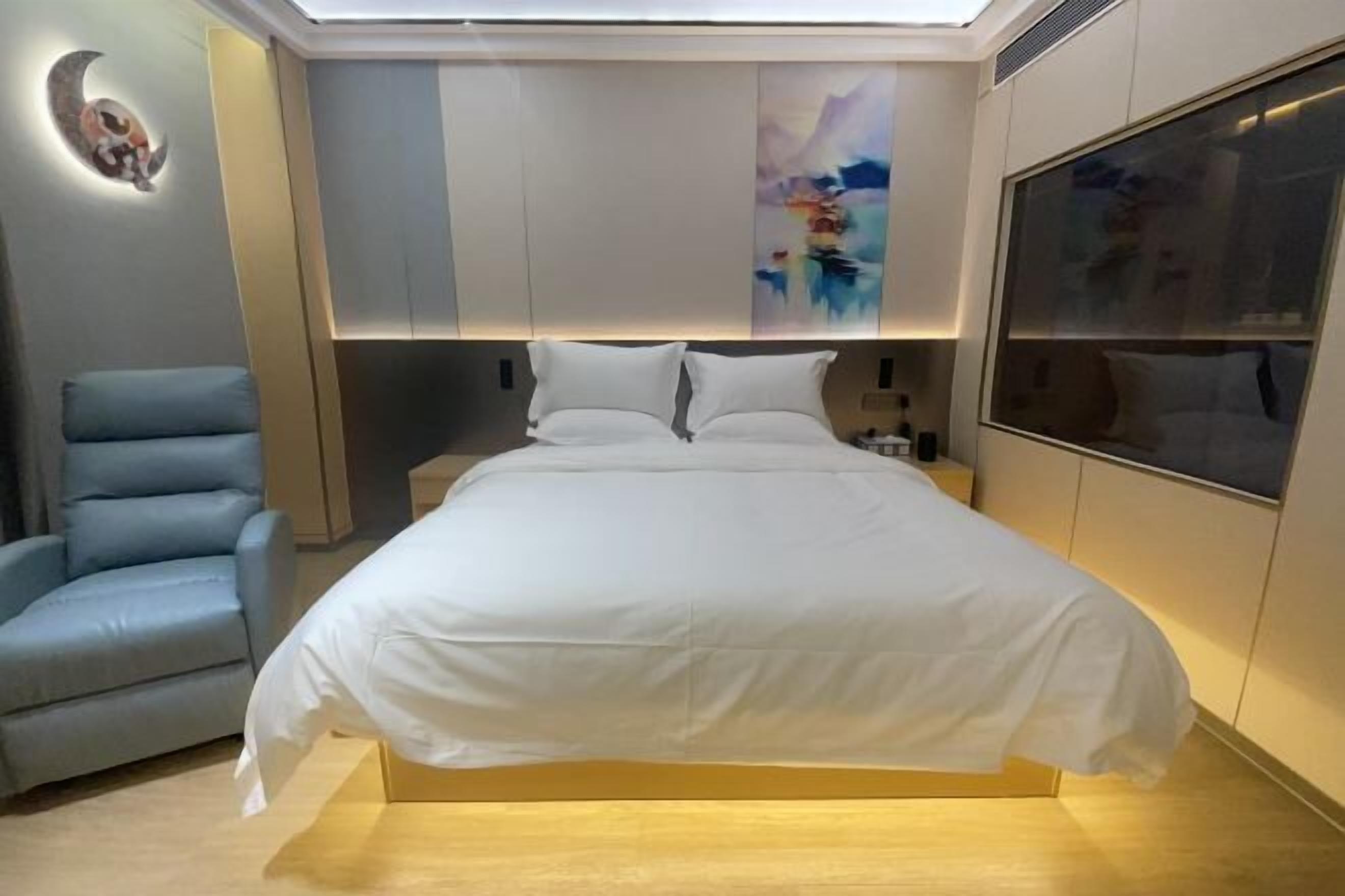 A modern bedroom with a bed, a blue chair, and a large window.