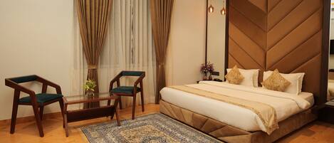 A bedroom with a large bed, a ceiling fan, a wooden headboard, and a small table with chairs.