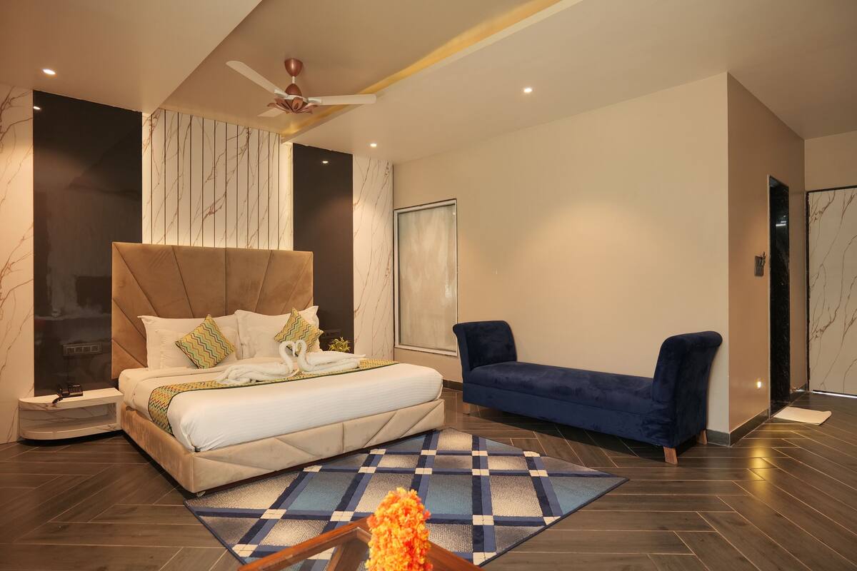 A modern bedroom with a large bed, a blue sofa, and a patterned rug.