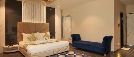 A modern bedroom with a large bed, a blue sofa, and a patterned rug.