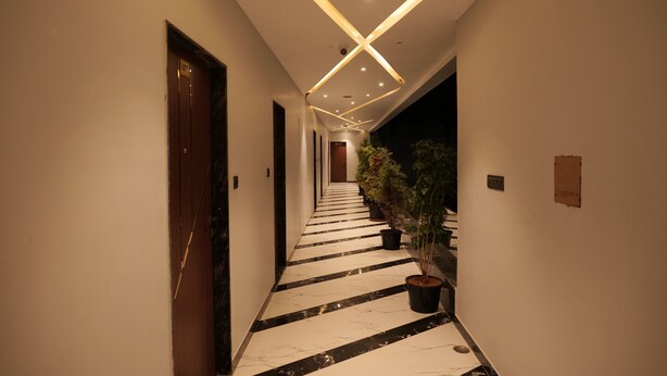 A hallway with a black and white marble floor, potted plants, and modern lighting fixtures. - Hotel 777, Pushkar (Pushkar)
