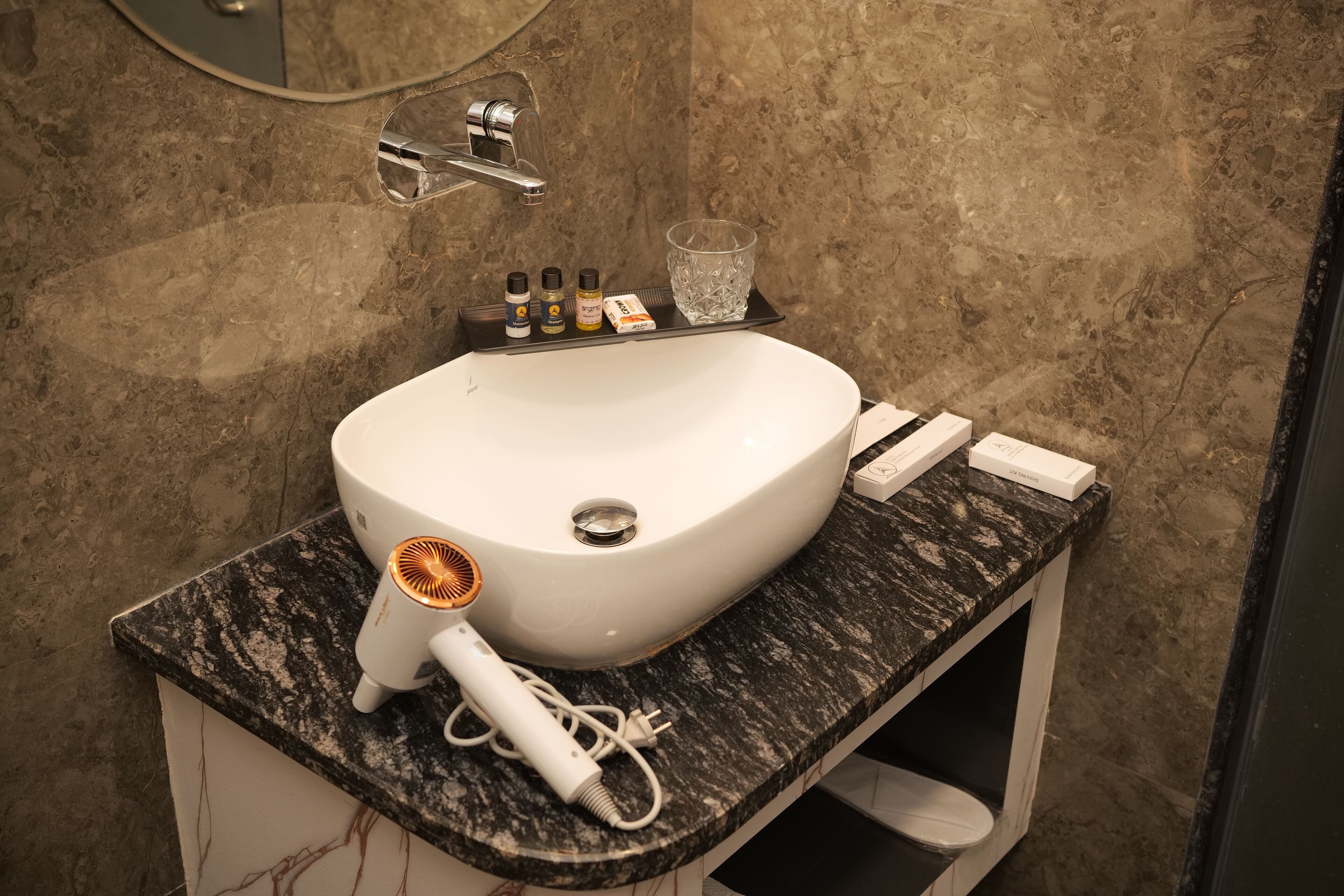 Ein Badezimmer mit einem weißen Waschbecken, einem Föhn und einer Ablage mit Pflegeprodukten.