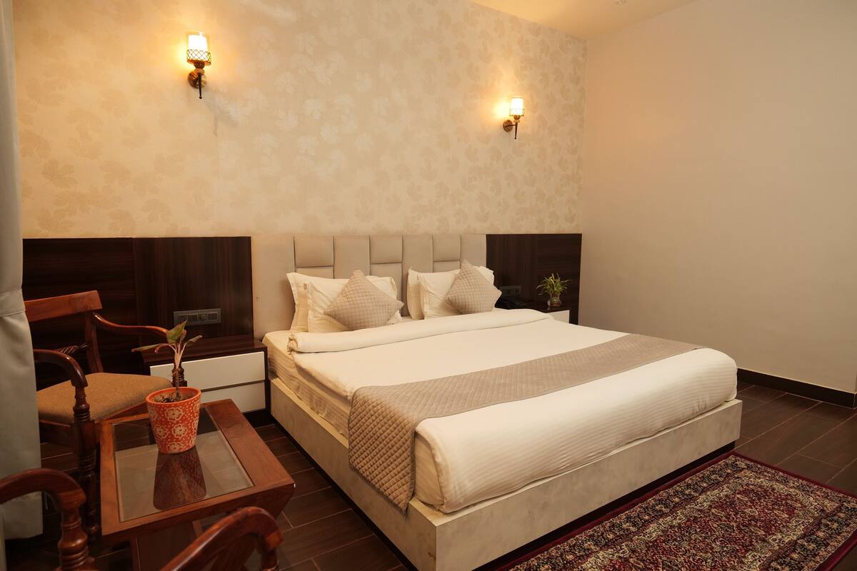 A neatly arranged bedroom with a bed, bedside tables, a small table with a plant, and two wall-mounted lamps.