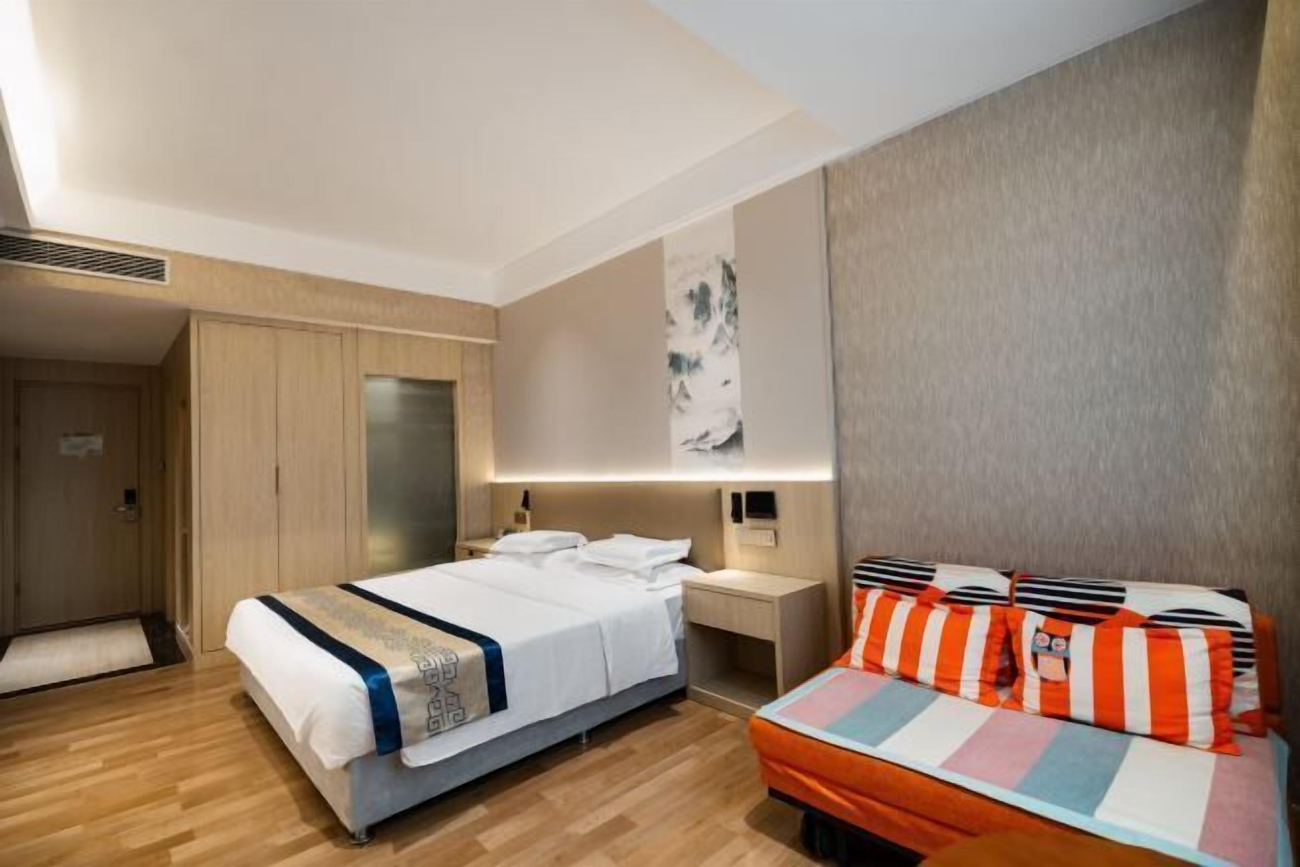Une chambre d’hôtel équipée d’un lit, d’une table de chevet et d’un luminaire fixé au mur.