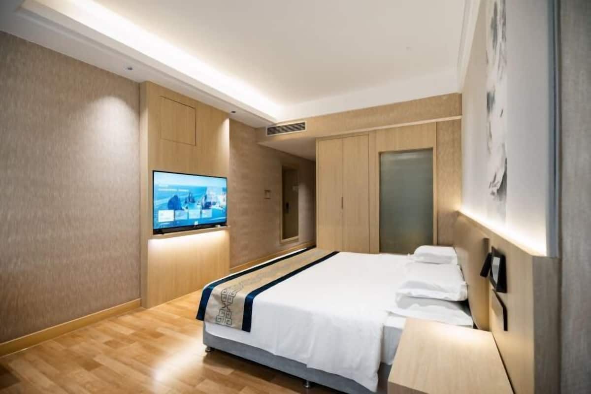 A modern hotel room with a bed, a television, and a wardrobe.
