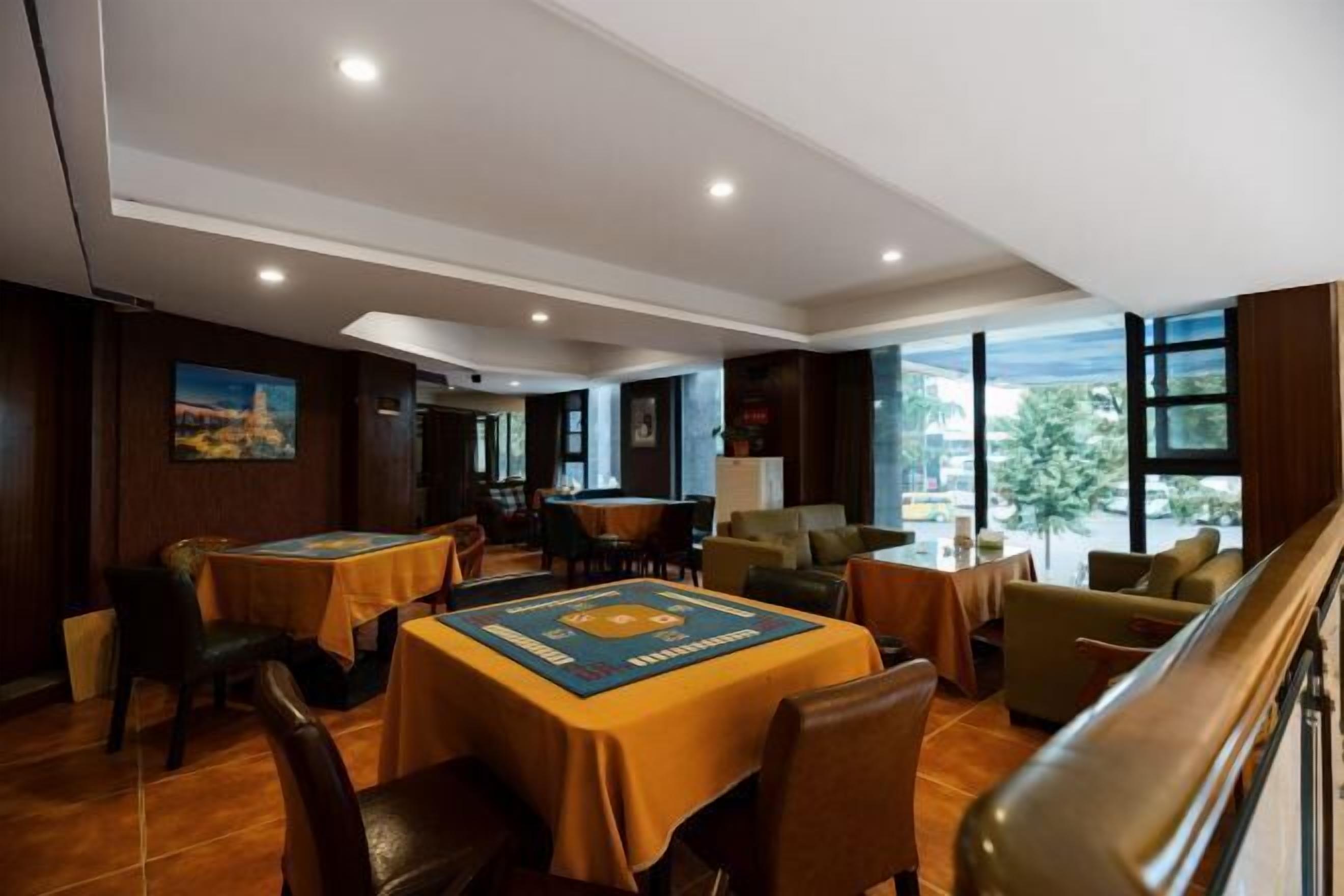 A hotel dining area with multiple tables, chairs, and a view of the outdoors through large windows.