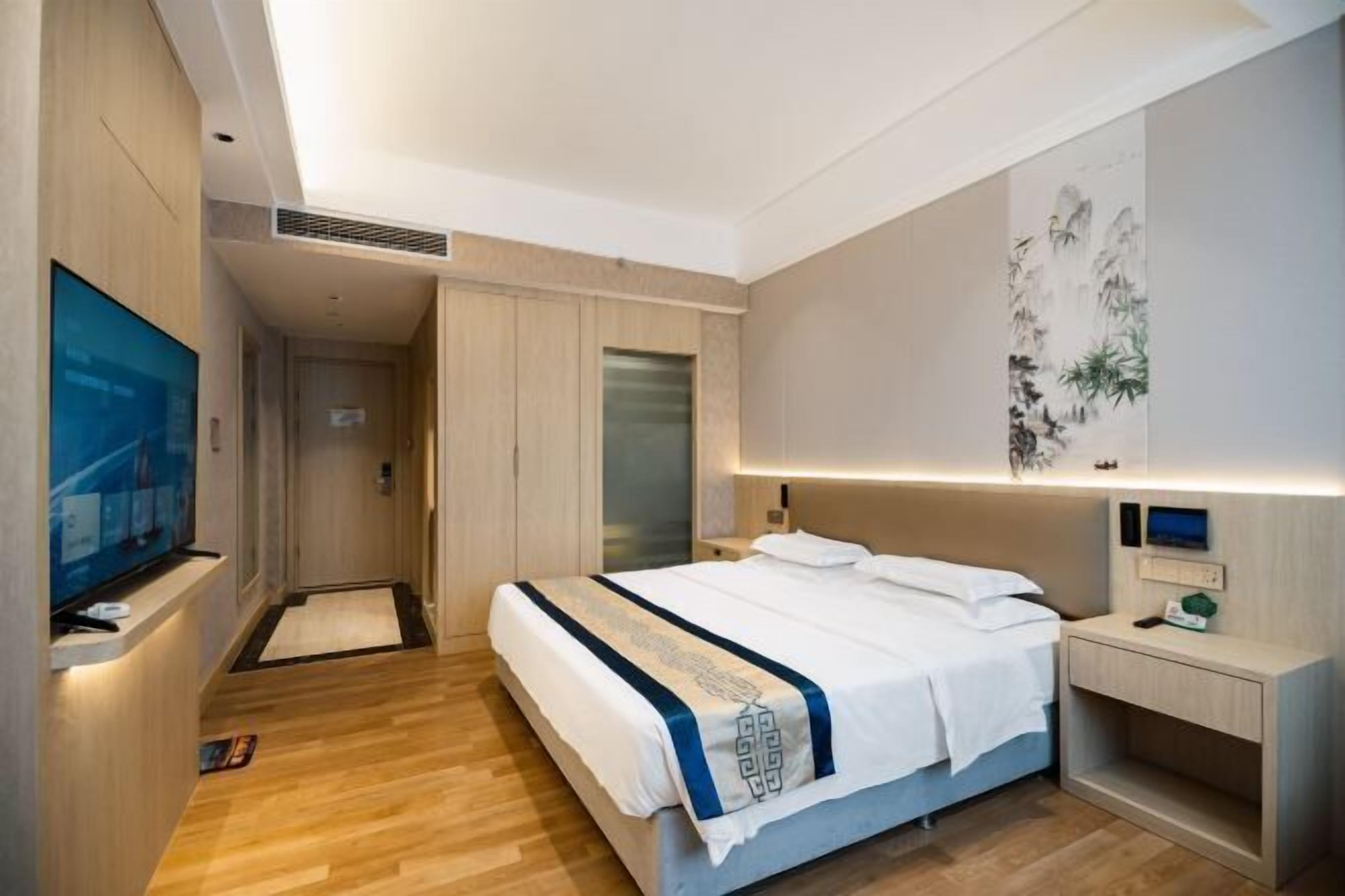 Une chambre d’hôtel équipée d’un lit, d’une télévision, d’un bureau et d’une œuvre d  ’art accrochée au mur.
