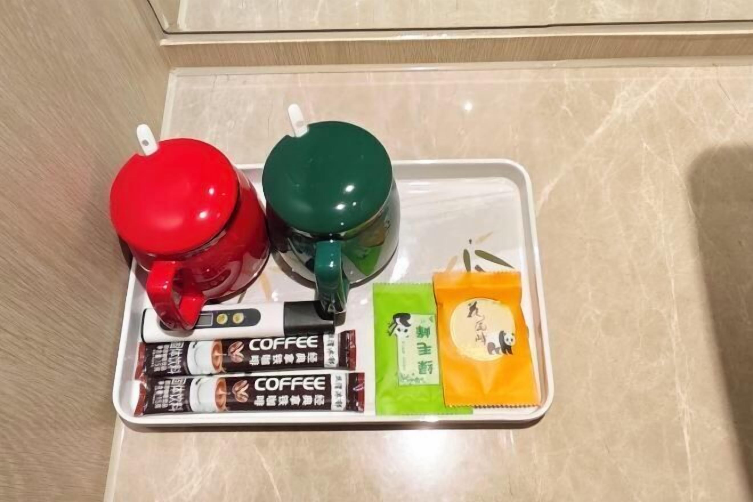 Een dienblad met twee thermoskannen, koffie en theezakjes.