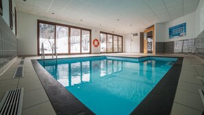 An indoor swimming pool with clear glass walls, a lifebuoy, and a control panel on the wall. - Wifi, swimming pool, terrace, balcony, parking, tv, ski locker, 24m², Les Bottières (Saint-Pancrace)