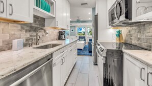 Una cocina moderna con armarios blancos, un lavamanos de acero inoxidable y un horno empotrado.