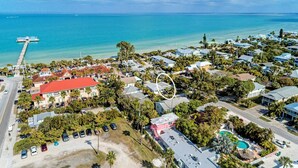 Vista aérea de una zona residencial costera con casas, un muelle y una piscina.