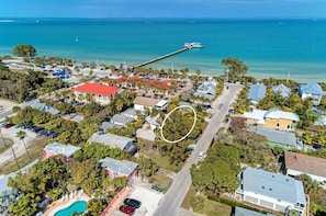 An aerial view of a coastal residential area with houses, a pier, and a swimming pool. - Dog friendly cottage - One block to the Bay! (Anna Maria)