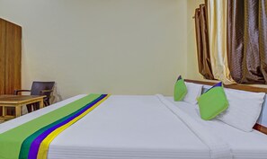A hotel room with a bed, a chair, and curtains. - Treebo Shalimar In The Forest (Karjat)